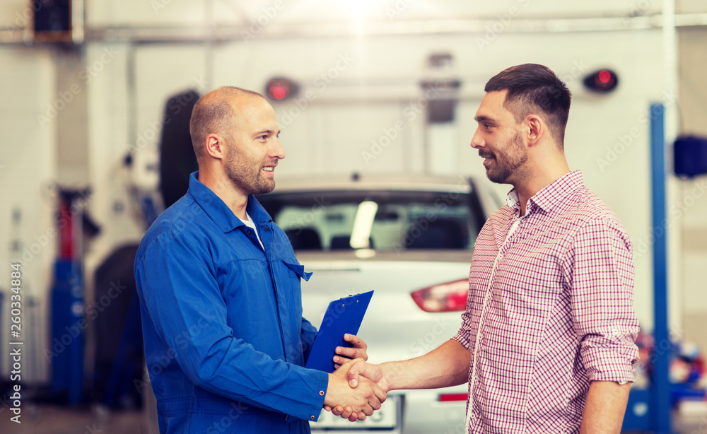 Obraz premium auto service, repair, maintenance, gesture and people concept - mechanic with clipboard and man or owner shaking hands at car shop