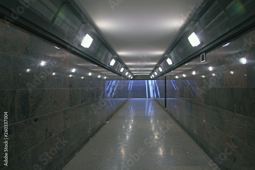 a pedestrian subway lined with granite and illuminated with lamps