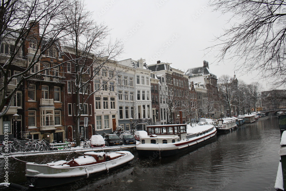 Snowy landscape in Amsterdam with boats on the river