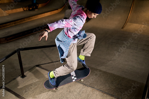 High angle action shot of contemporary young man doing skating stunt at skateboard park, shot with flash