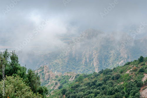 Mountains near Montserrat Abbey in Spain. Clouds and fog. Trees on cliffs.