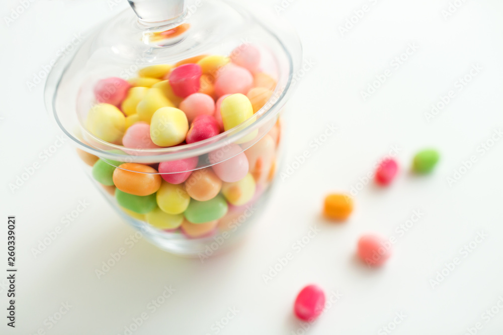 food, confectionery and sweets concept - close up of glass jar with colorful candy drops over white background food, confectionery and sweets concept - close up of glass jar with colorful candy drops over white background