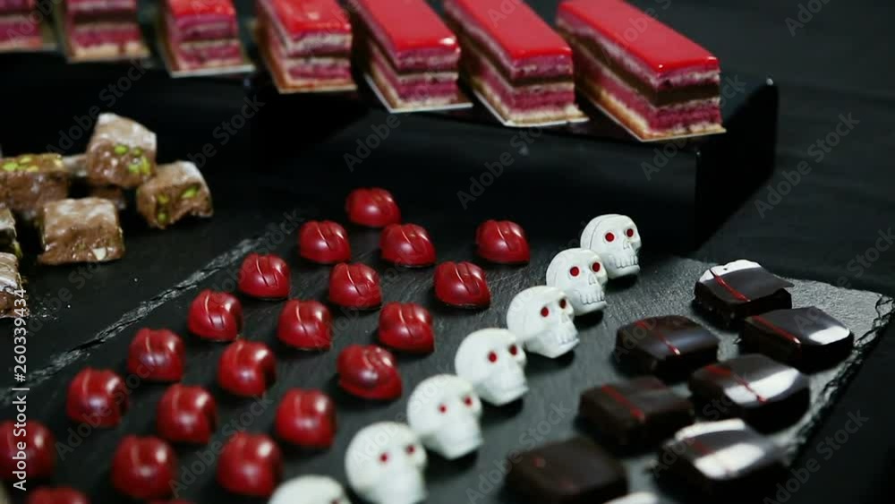 closeup panorama down at assorted candy bar table with cream cakes, mousse mini tarts, and chocolate candies closeup panorama down at assorted candy bar table with cream cakes, mousse mini tarts, and chocolate candies