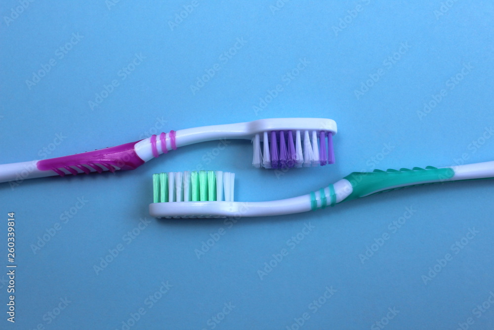 Two toothbrushes lie against each other on a blue background Two toothbrushes lie against each other on a blue background