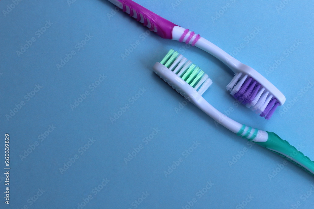 Two toothbrushes lie against each other on a blue background Two toothbrushes lie against each other on a blue background