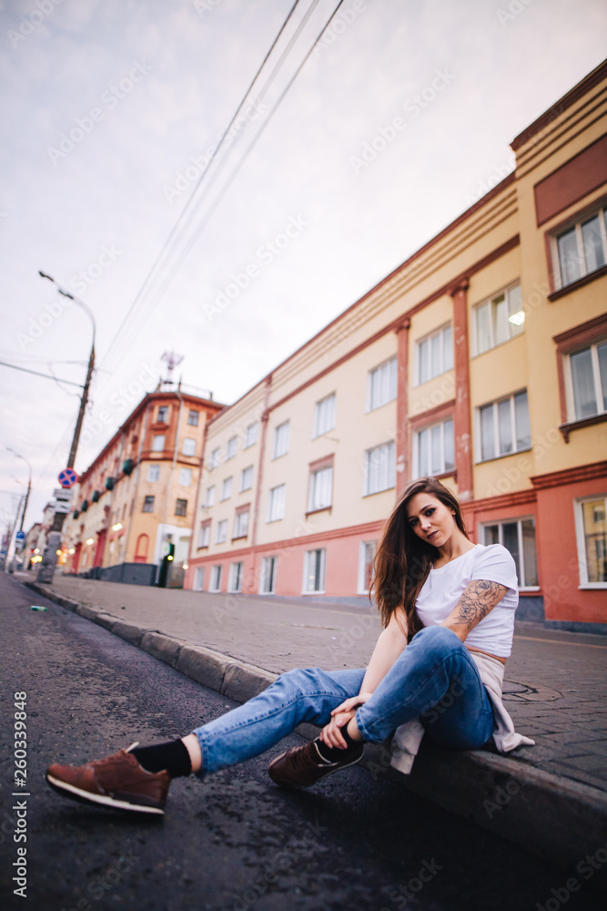 The girl sits on the edge of the roadway. Street urban style. The girl sits on the edge of the roadway. Street urban style.