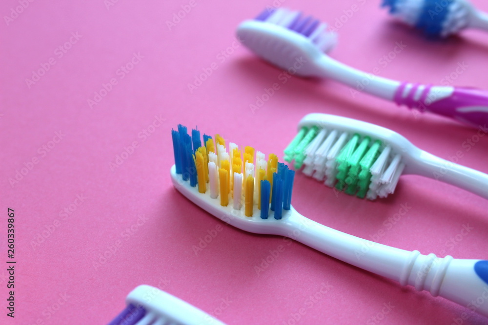 Multi-colored toothbrushes lie on a pink background Multi-colored toothbrushes lie on a pink background