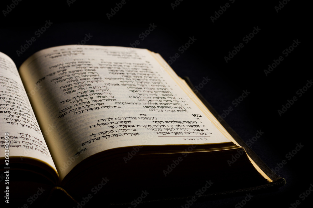 Open hebrew Bible, isolated on black background, with side lighting