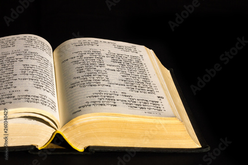 Open hebrew Bible, isolated on black background, with front lighting