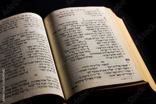 Open hebrew Bible, isolated on black background, with side lighting