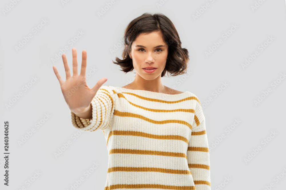 restriction, prohibition and people concept - young woman in striped pullover making stopping gesture over grey background restriction, prohibition and people concept - young woman in striped pullover making stopping gesture over grey background