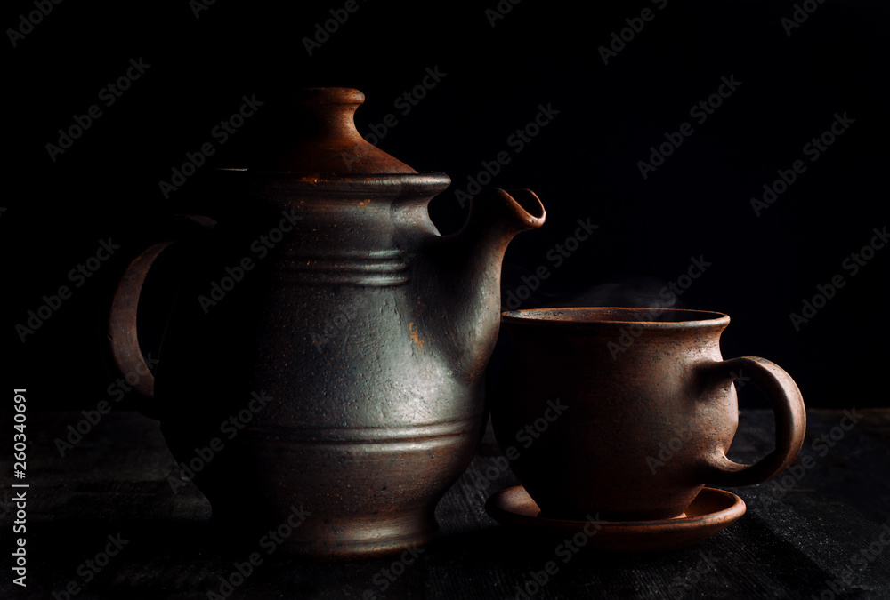 Tea cup and teapot, on a wooden table, beautiful sunshine and black background.