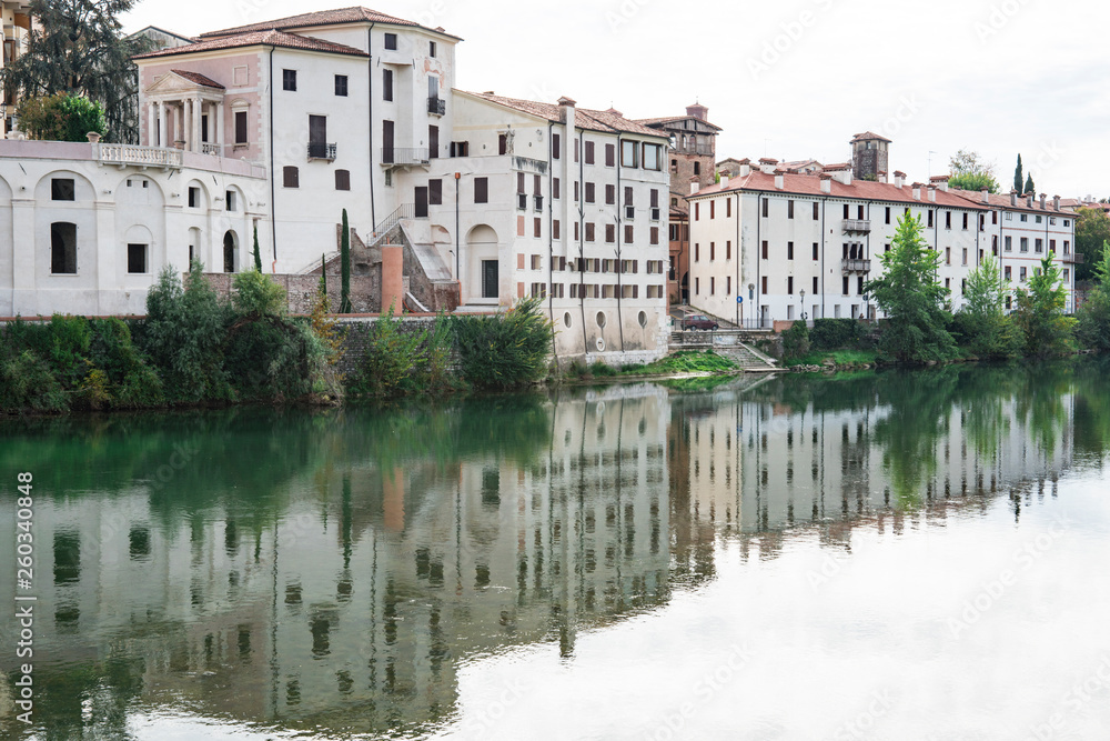 white houses  along river Brenta in Bassano del Grappa, Italy. With reflection in water