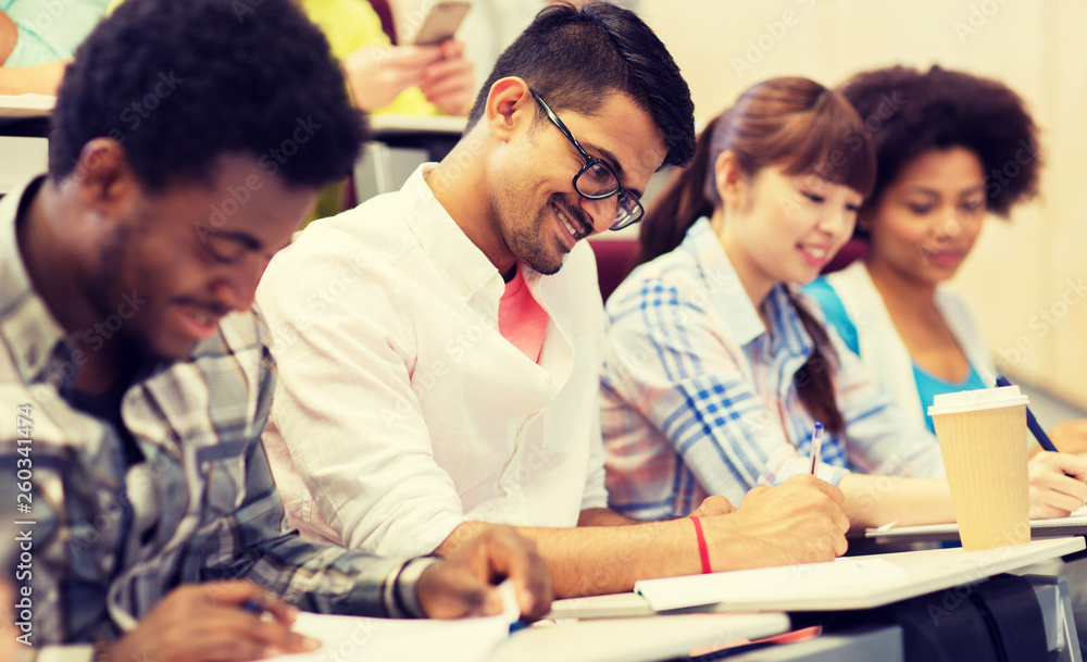 education, high school, university, learning and people concept - group of international students with notebooks and coffee writing test in lecture hall education, high school, university, learning and people concept - group of international students with notebooks and coffee writing test in lecture hall