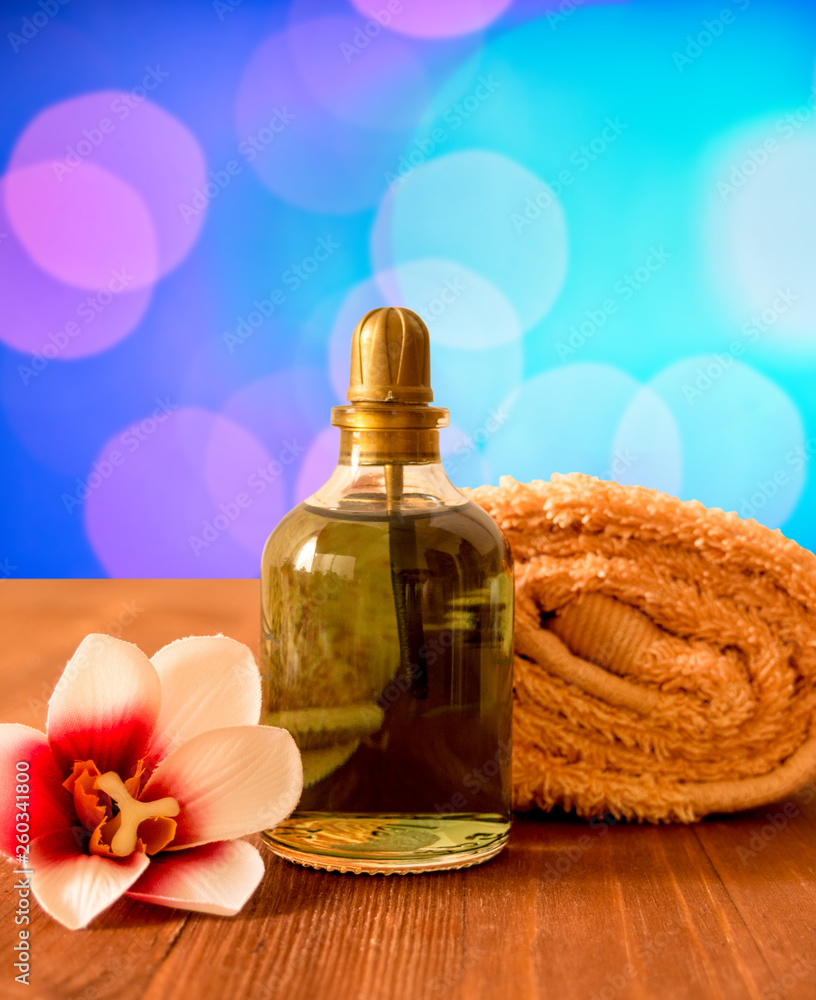 Towel, bottle with oil and orchid flower on wooden background Towel, bottle with oil and orchid flower on wooden background