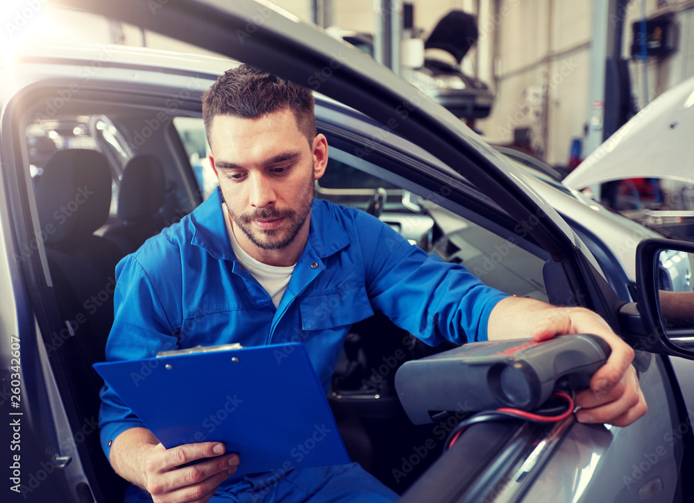 service, repair, maintenance and people concept - mechanic man with automotive diagnostic scanner and clipboard checking car system at workshop service, repair, maintenance and people concept - mechanic man with automotive diagnostic scanner and clipboard checking car system at workshop