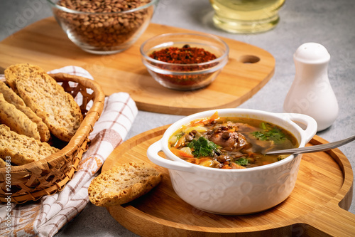 Lentil soup with chicken in a white bowl on a wooden board on a gray table and ingredients