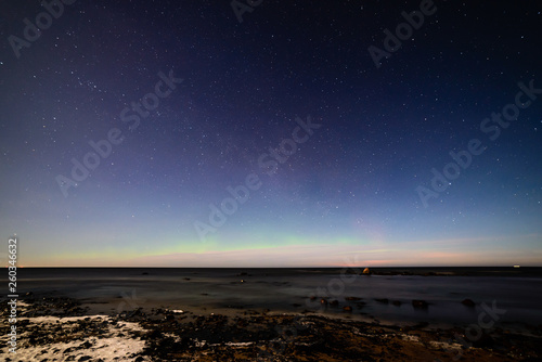 aurora borealis and stars in dark night over sea beach in winter © Martins Vanags