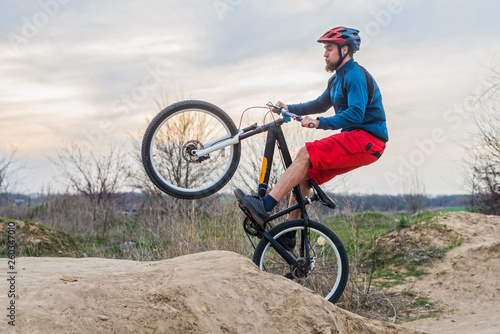 Man on a mountain bike in red shorts and blue sweater performing a dirt jump. Active lifestyle.