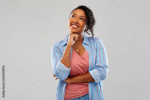 people, inspiration and dream concept - happy african american young woman dreaming over grey background