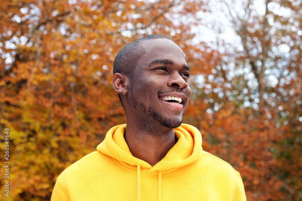 © mimagephotos - Close up handsome young african american man smiling against autumn leaves in background © mimagephotos - Close up handsome young african american man smiling against autumn leaves in background