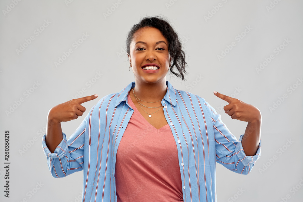 Φωτογραφία people, gesture and personality concept - happy african american young woman poi