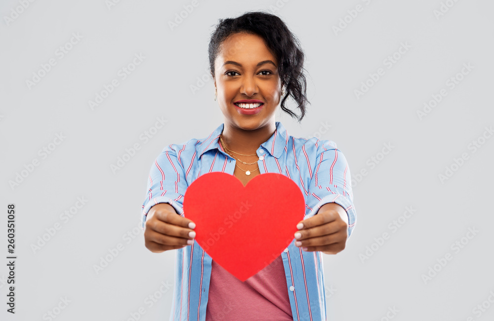 love, valentine's day and charity concept - happy african american young woman with red heart over grey background love, valentine's day and charity concept - happy african american young woman with red heart over grey background