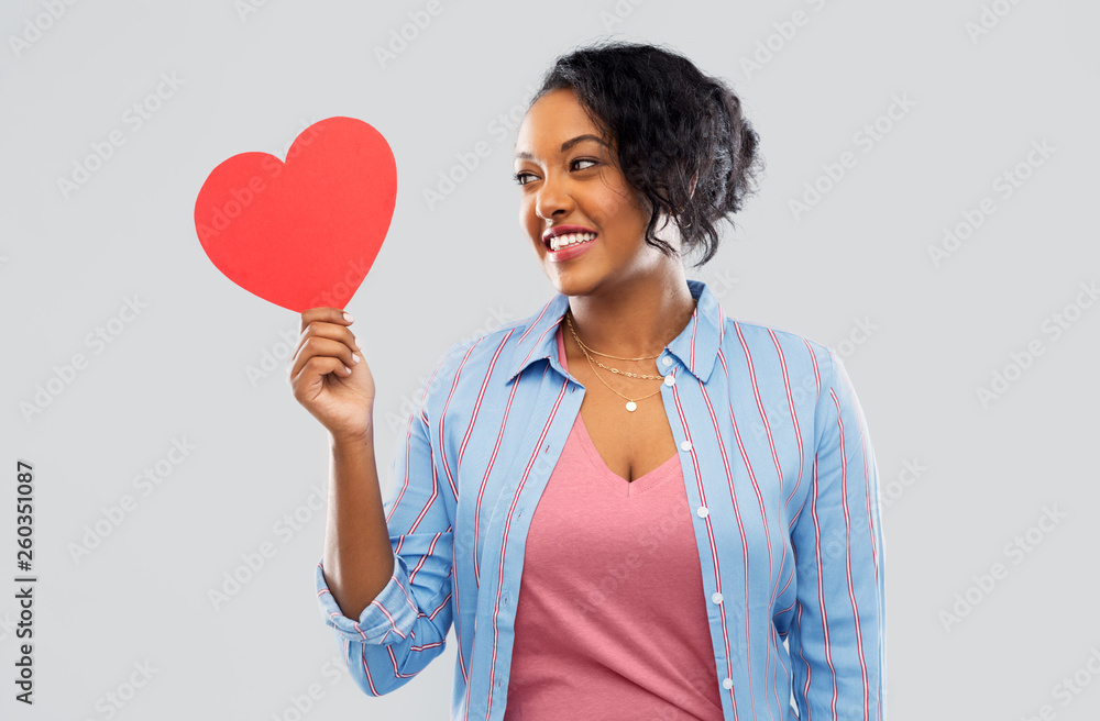 love, valentine's day and charity concept - happy african american young woman with red heart over grey background love, valentine's day and charity concept - happy african american young woman with red heart over grey background