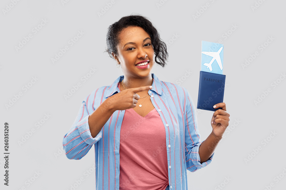 travel, tourism and people concept - happy african american young woman showing passport and air ticket over grey background travel, tourism and people concept - happy african american young woman showing passport and air ticket over grey background