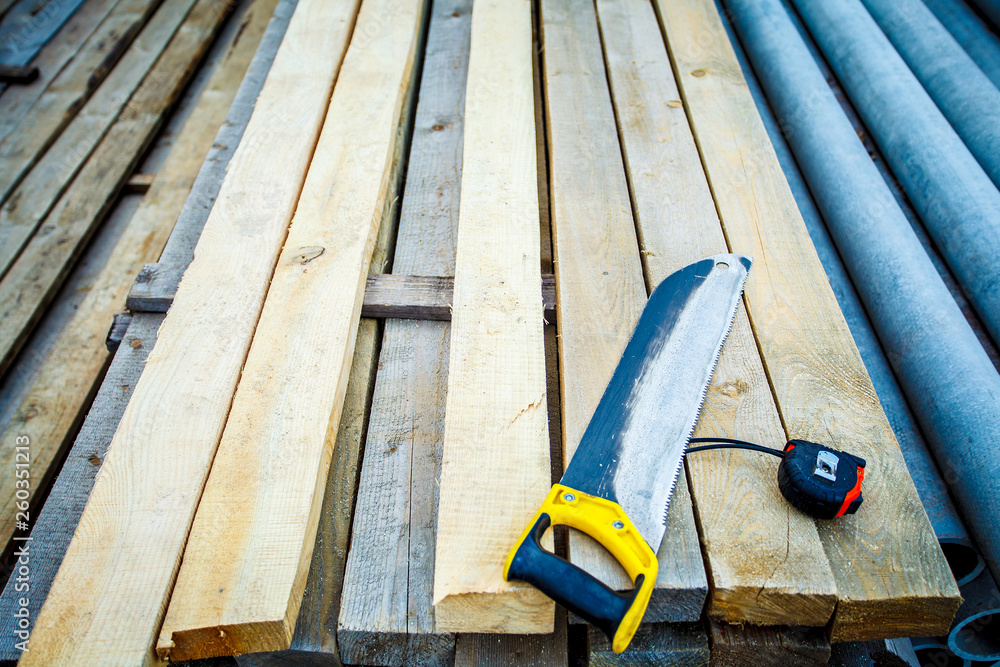 saw with a construction tape measure on wooden boards. Saw. Construction tape. Wooden planks saw with a construction tape measure on wooden boards. Saw. Construction tape. Wooden planks