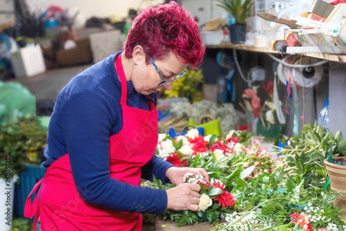 Portrait of female florist creating beautiful bouquet at flower shop . © herraez