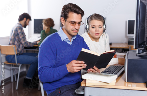 Female and male students working in computer room in library