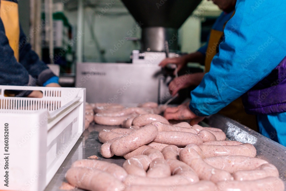 Workers process meat sausages at the meat factory sausage production of fresh meat
