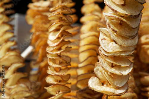 Fried potato chips on stick, Spiral potatoes fried, on wooden sticks, spiral. Selling food at the market. Unhealthy fried street food.
