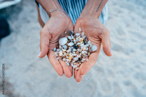 Women's hands are holding a lot of small pebbles
