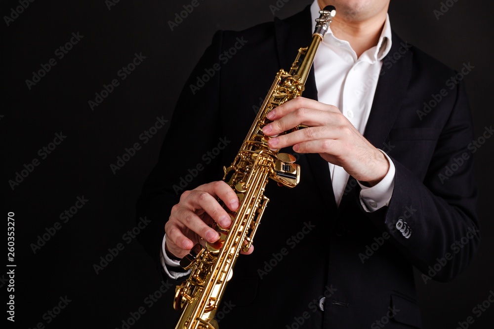 Fototapeta premium Saxophonist in a black classic suit playing the soprano saxophone