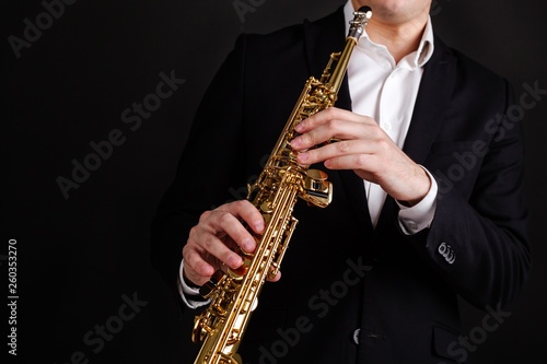 Saxophonist in a black classic suit playing the soprano saxophone