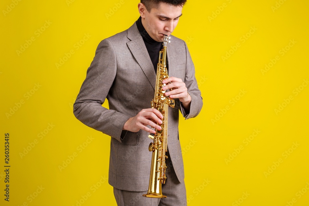 Fototapeta premium Saxophonist plays jazz music on soprano saxophone on yellow