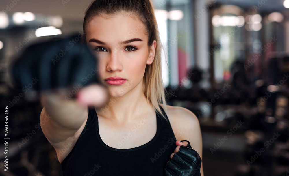 Young girl or woman with gloves, doing exercise in a gym.