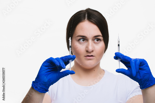 Young woman making anti-aging injections to increase the lips isolated on white background .