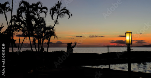 Silhouette of a Hawaiian hula dancer performing near the ocean at sunset with palm trees on the beach  Lahaina  Maui  Hawaii