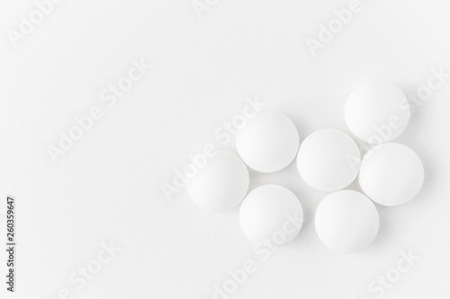 White pills on a light background close-up. Minimalistic image suitable as a background on the theme of medicine and health.