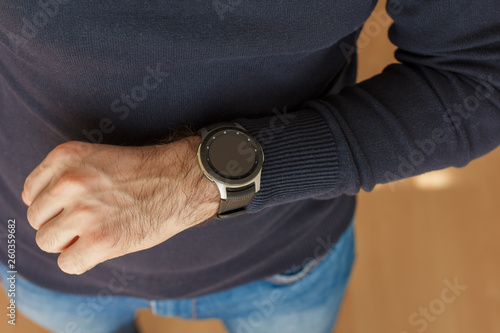 Business Man uses a smart watch on his hand inside of the office. Close up look.