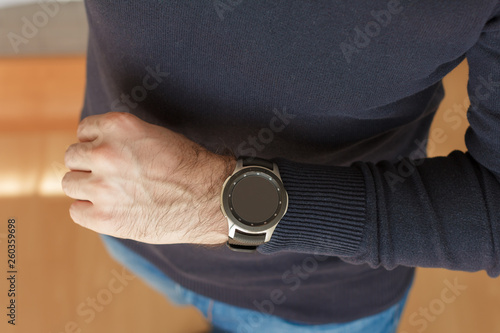 Business Man uses a smart watch on his hand inside of the office. Close up look.