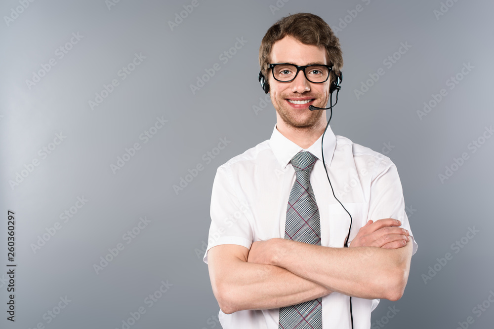 smiling call center operator in glasses and headset with crossed arms on grey background smiling call center operator in glasses and headset with crossed arms on grey background