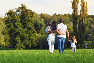 Rear view. Happy family with children walking in the park. 