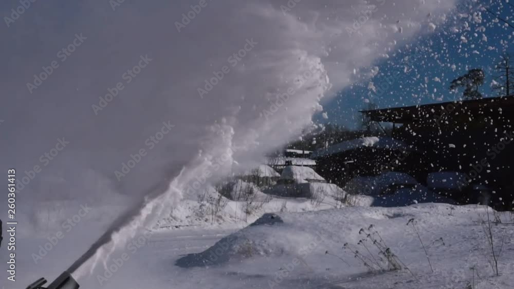 A man cleans the snow with a snowblower in sunny winter weather. A man cleans the snow with a snowblower in sunny winter weather.
