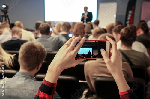 Woman takes a picture during the conference using smartphone