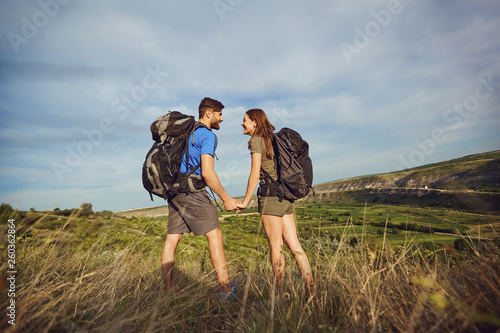 Happy couple of tourists with backpacks in nature