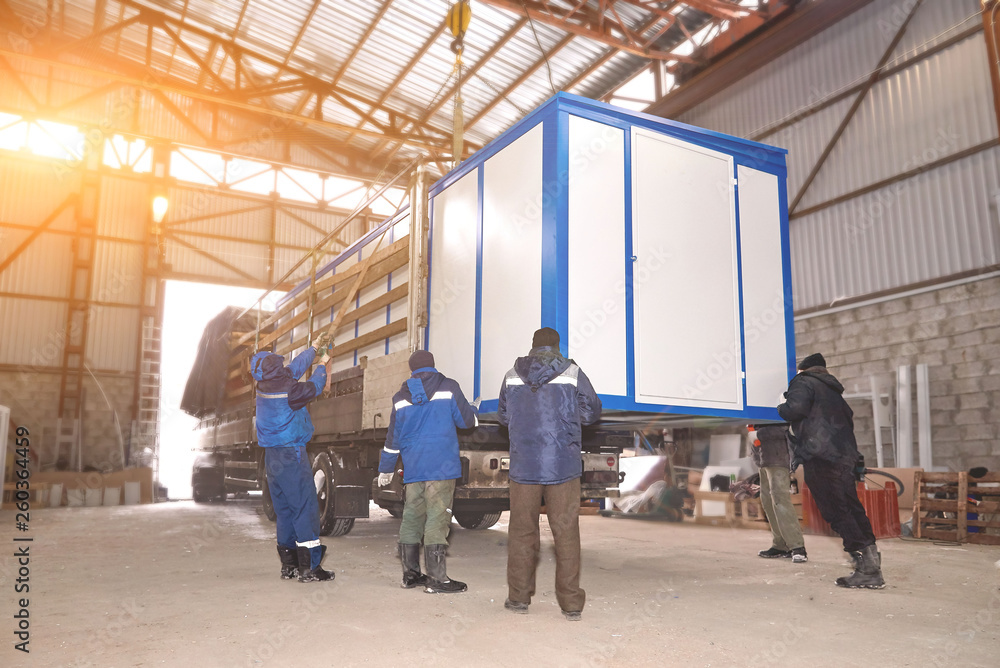 Men loaded transformer substation in a truck.